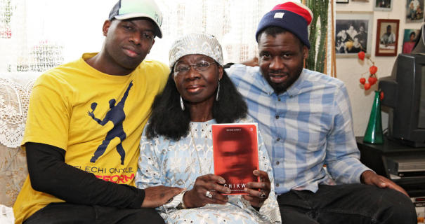 Mrs Onyele, pictured with her sons Kelechi and Chima, holding a copy of her book Chikwe: Es bleibt ein Traum. The novel, written in German and whose title roughly translates as “A Forlorn Dream”, chronicles the life of the eponymous Chikwe from a rural community in southeastern Nigeria to the German city of Frankfurt │© Menzel/Amani Verlag